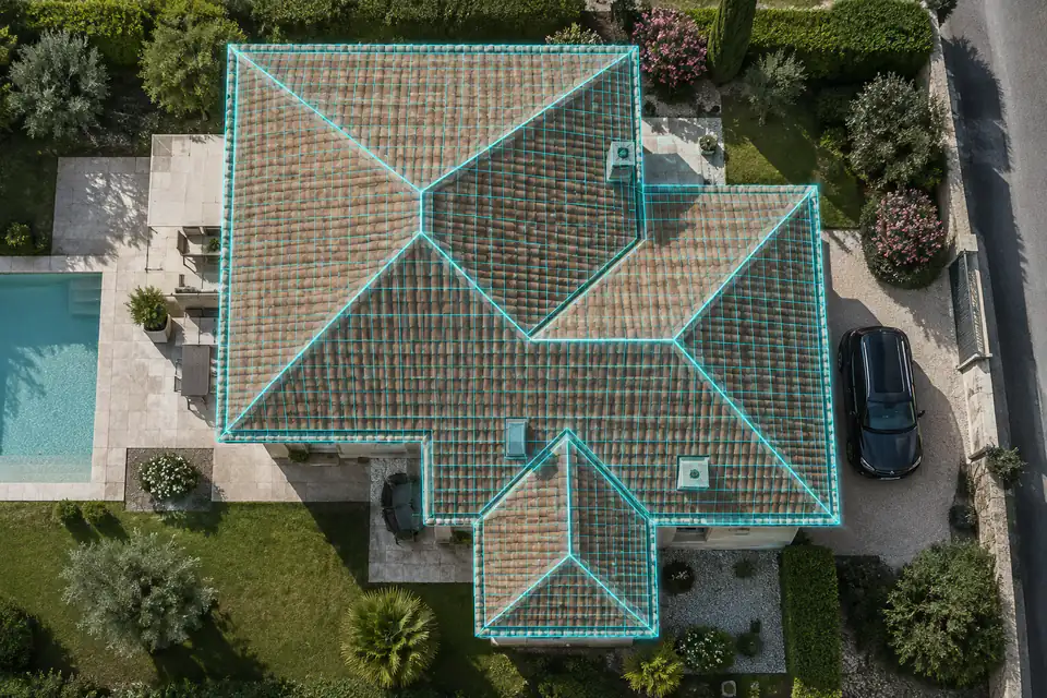 Vue aérienne d'une maison au toit de tuiles à plusieurs pans, chaque pan et les gouttières soulignés par un relevé 3D
